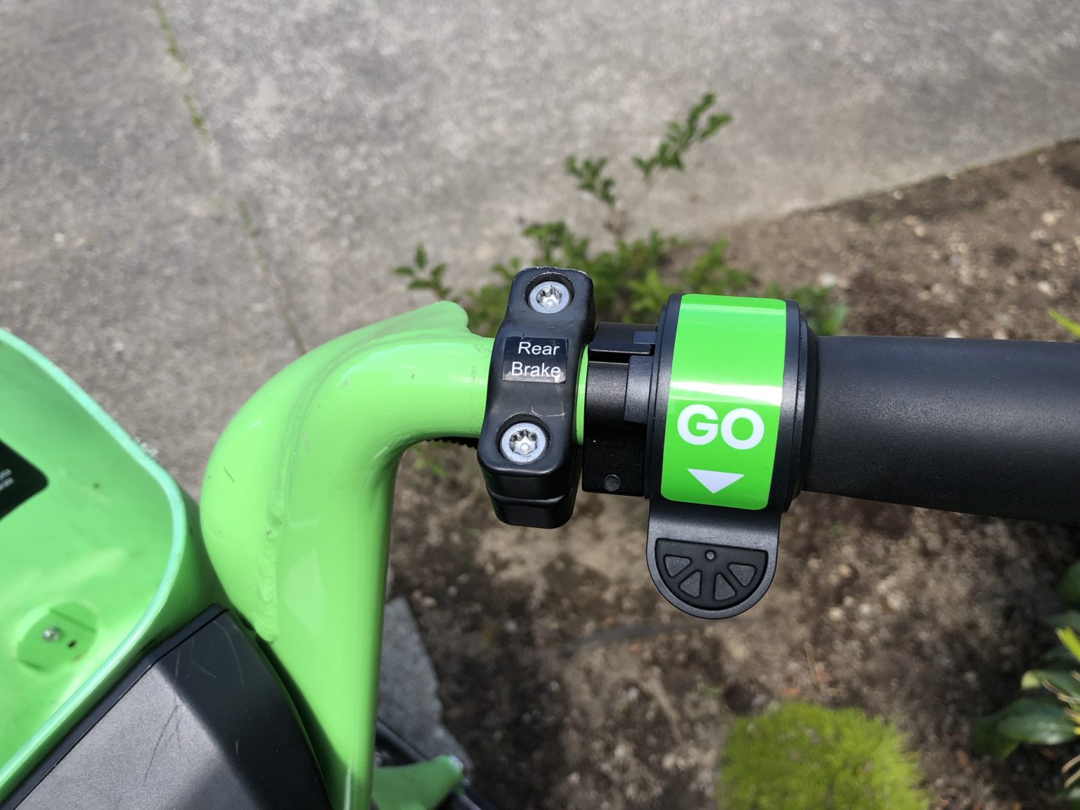 Lime e-bike handlebar with the green GO throttle paddle beside the pedal-assist controls