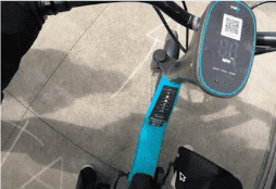 Evidence photo: a rider pointing a phone at the handlebar QR code