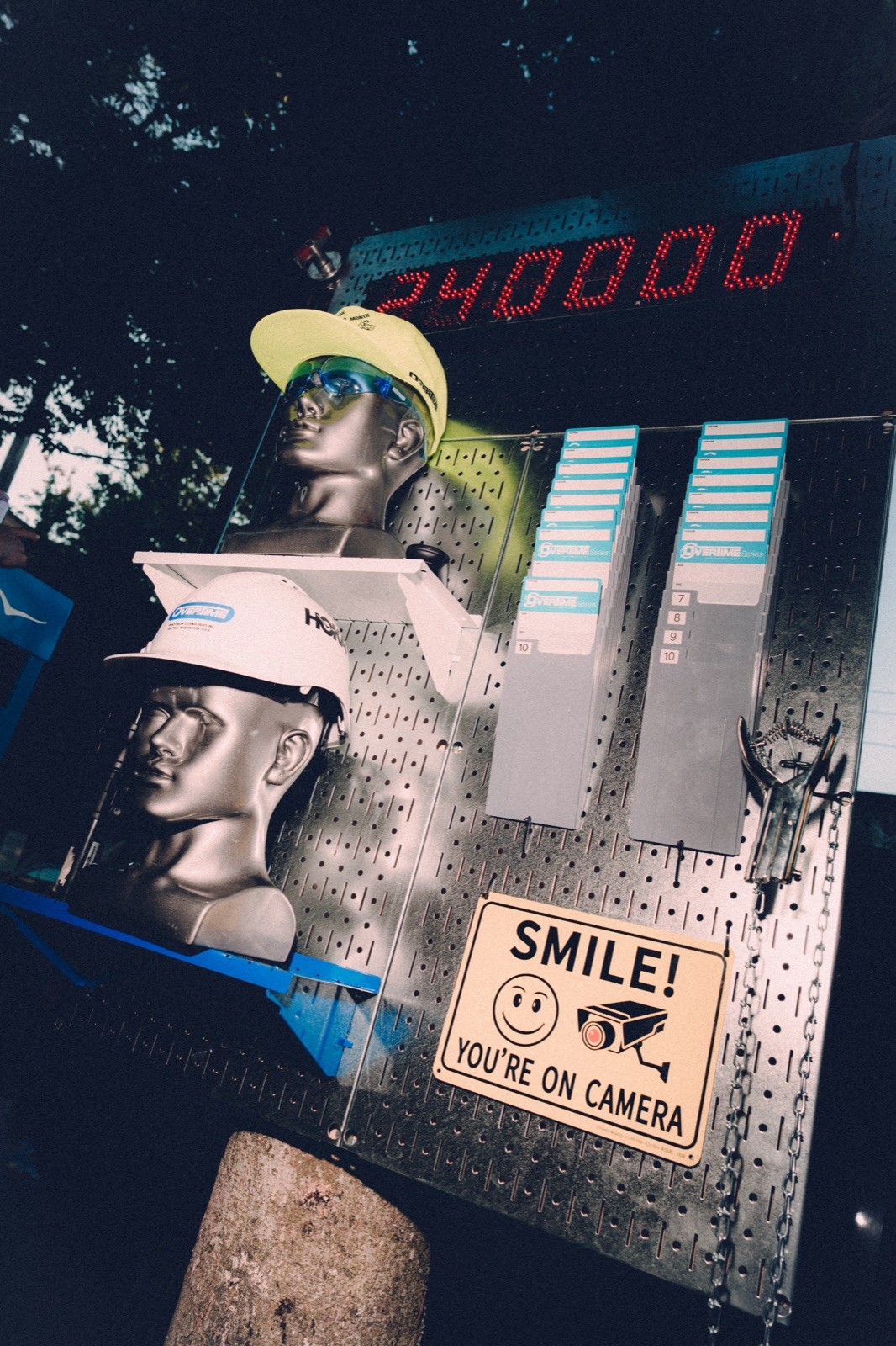 Race-day rig: hard hats on a pegboard beside a red LED clock reading 24:00:00